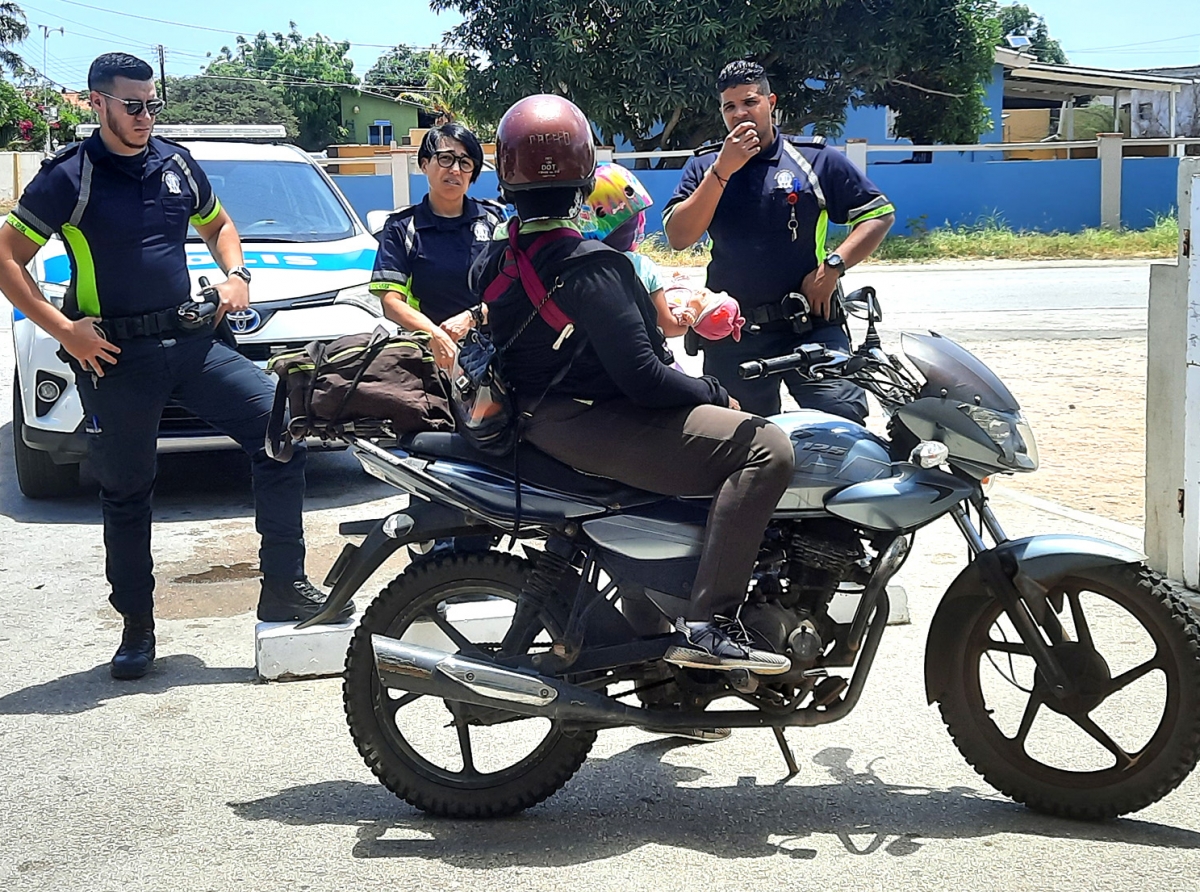 Polis a hala atencion di motociclista coriendo cu un mucha chikito sinta su dilanti