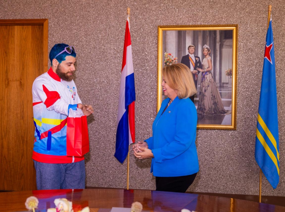 Atleta Elliot Loonstra ta regala Prome Minister un t-shirt y varios pin di e Weganan Paralimpico